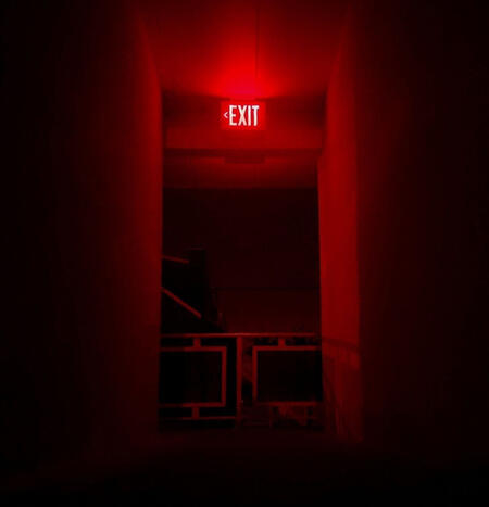 this is a black and red aesthetic image of an empty hallway with an 'exit' sign at the top