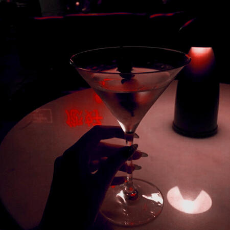 this is a red-tinted image of a hand holding a martini glass